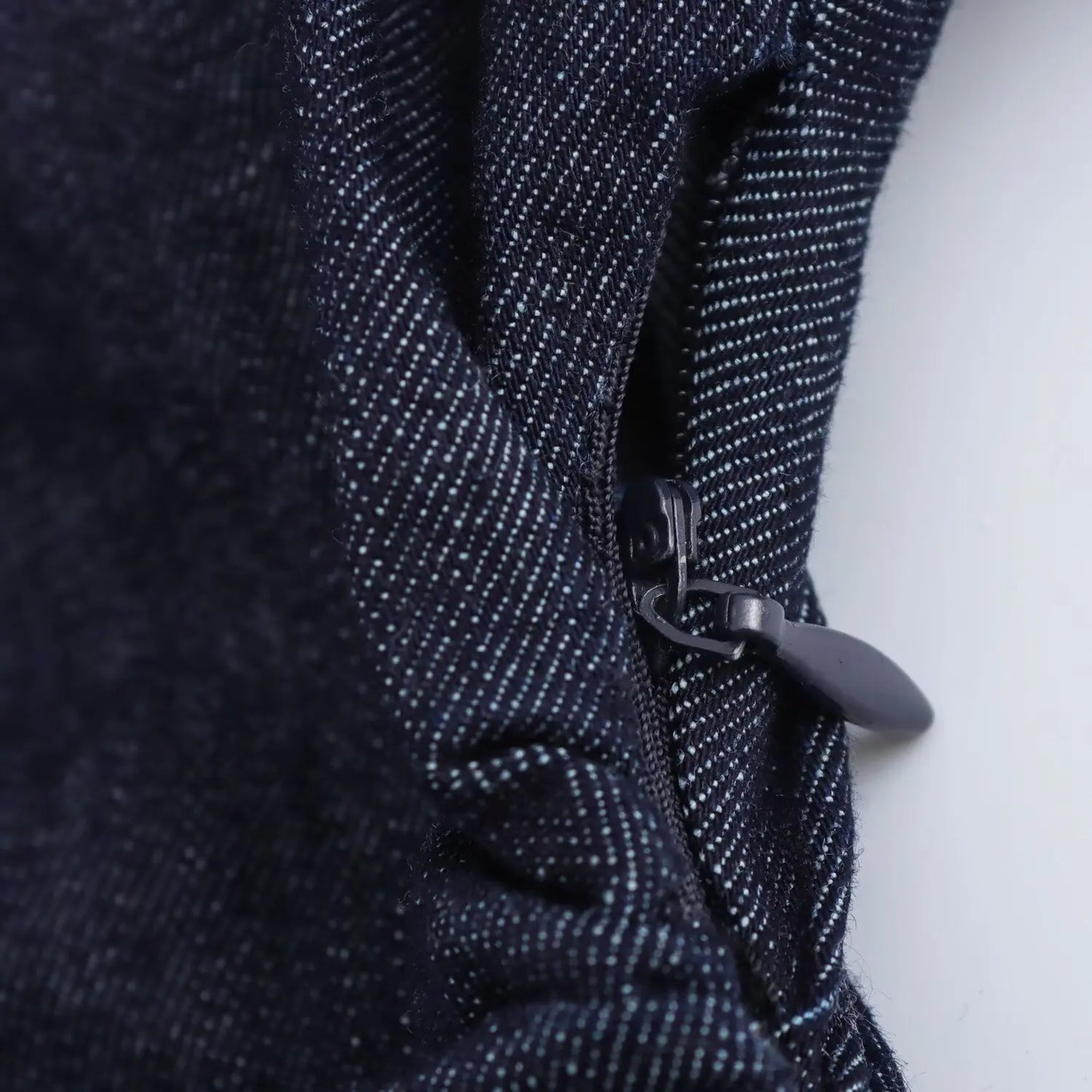 Close-up of a dark blue denim dress with a zipper on a white background