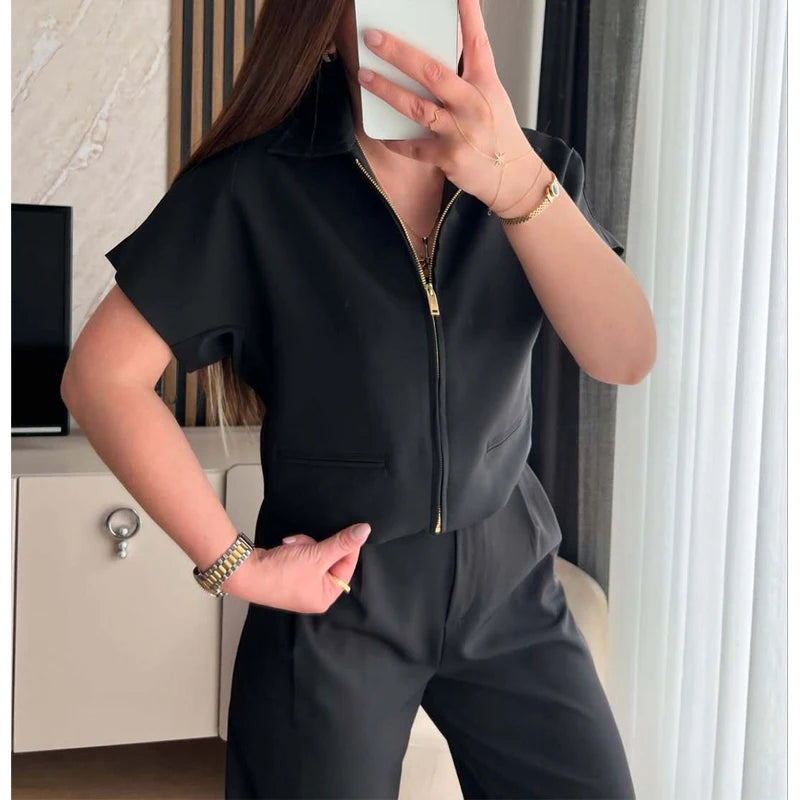 Person wearing a black zip-up jumpsuit in an indoor setting.