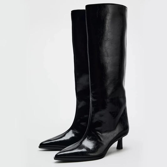 Pair of black knee-high boots on a light gray background