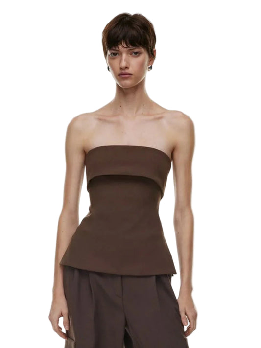 Woman wearing a brown strapless top and pants on a white background