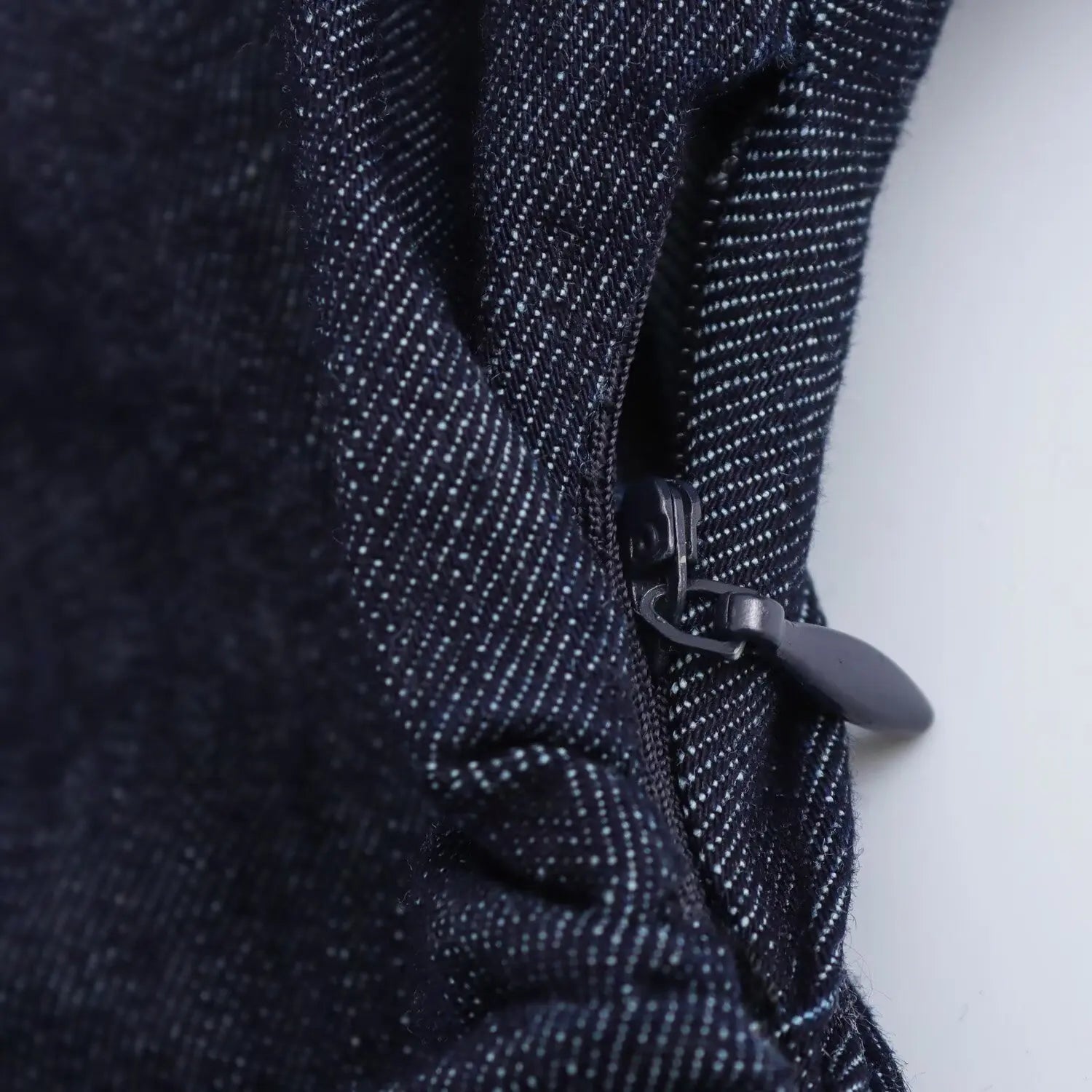 Close-up of a dark blue denim dress with a zipper on a white background