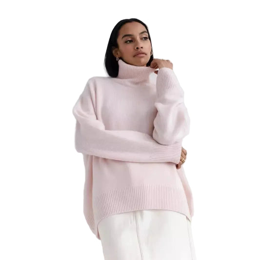 Person wearing a light pink turtleneck sweater against a white background
