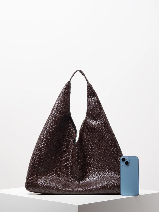 Brown textured handbag next to a blue phone on a light gray background