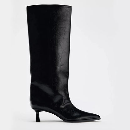 Black knee-high boot on a light gray background