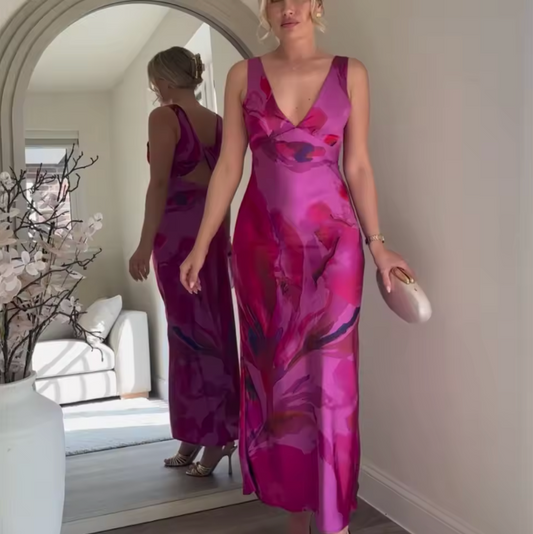 Woman in a vibrant pink and purple dress standing in front of a mirror.